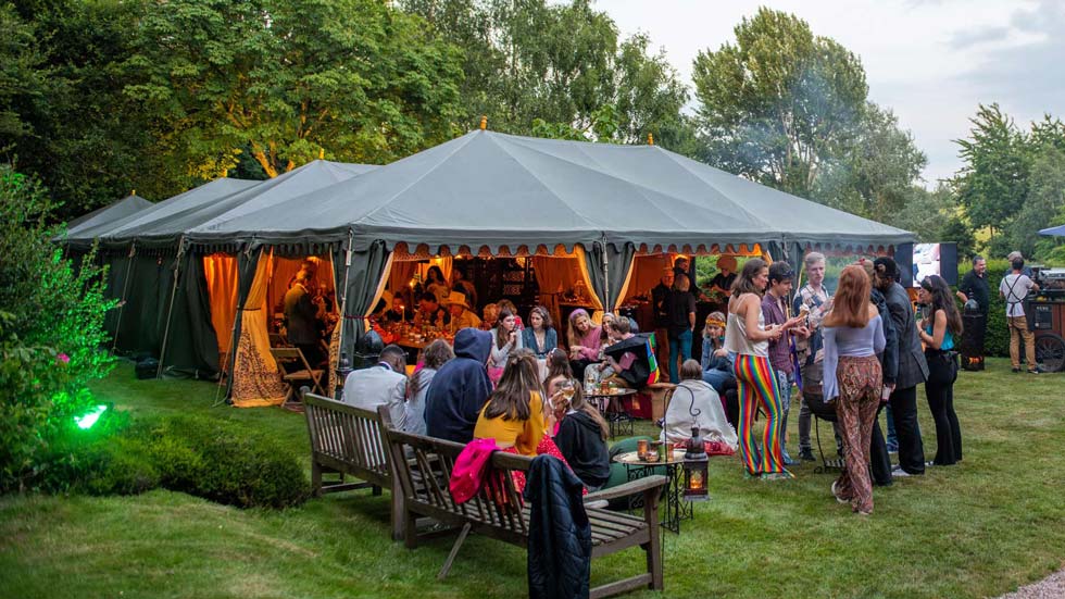 A group of young adults socialising and celebrating outside of a Bedouin tent at an 18th birthday party.