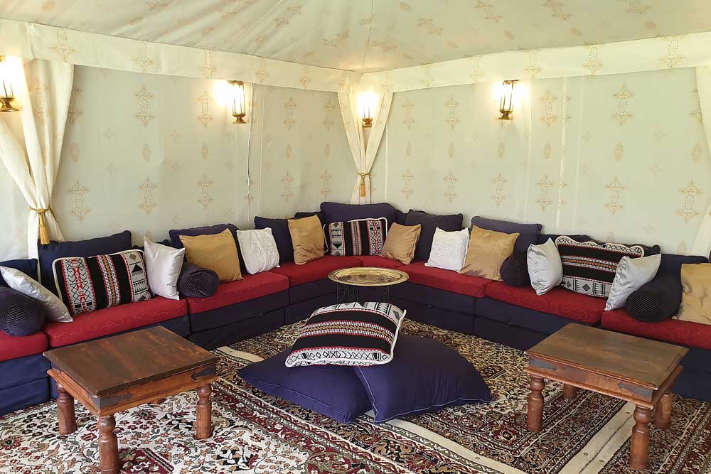 A 9x6m Bedouin tent with Jasmine lining and low-level Chillout Seating Cushions.