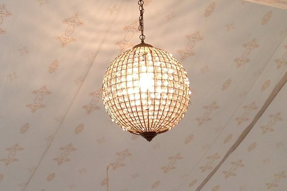 A Globe Chandelier in the Roof of a Jasmine Lined Tent.