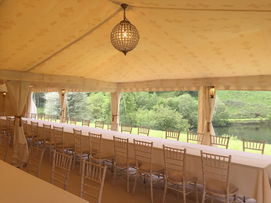 A 9x18m Wedding tent with cream Jasmine linings (featuring gold Indian print) with tables and chairs.