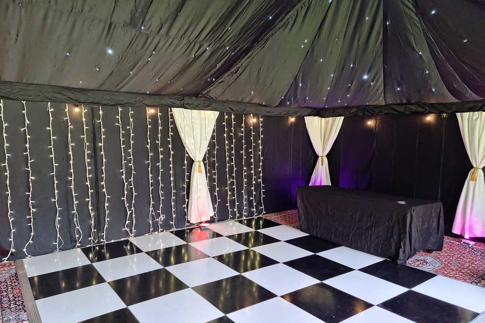 A black and white chequered dancefloor inside a party tent.