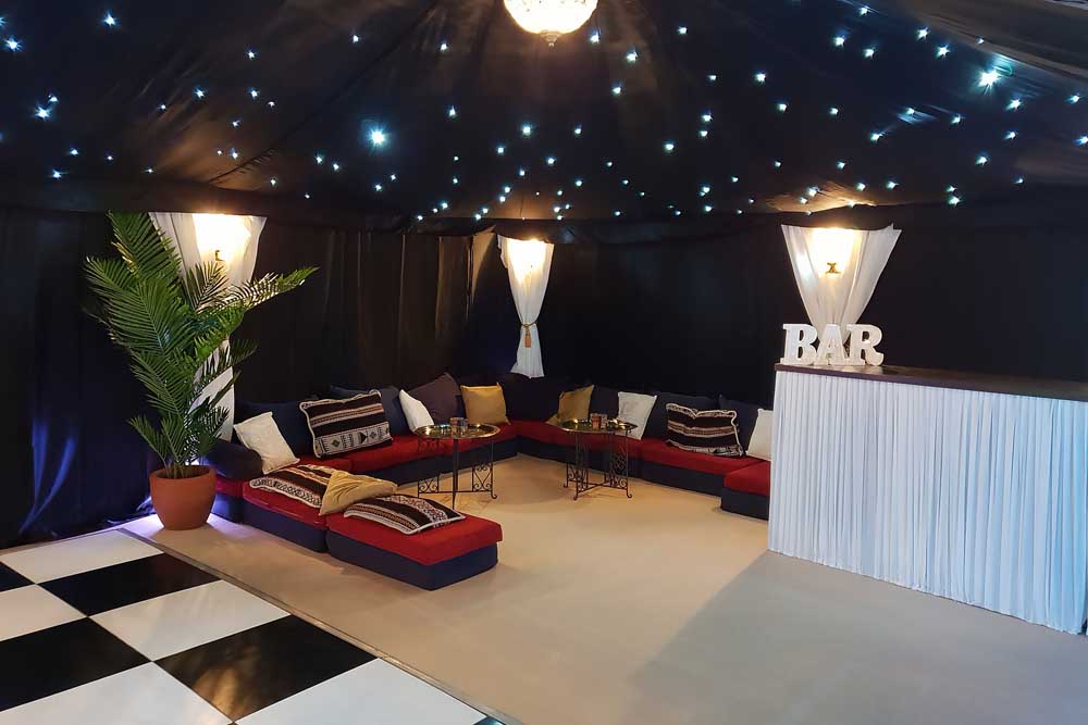 A 9x6m Bedouin Tent with Starcloth Linings, Low-Level Chillout Seating, Bar and Black and White Dancefloor.