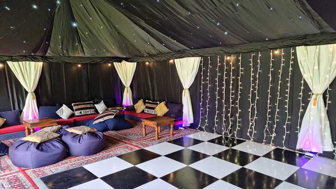 Starcloth Party Tent Interior with burgundy persian carpets, Low-level seating and black and white dance floor