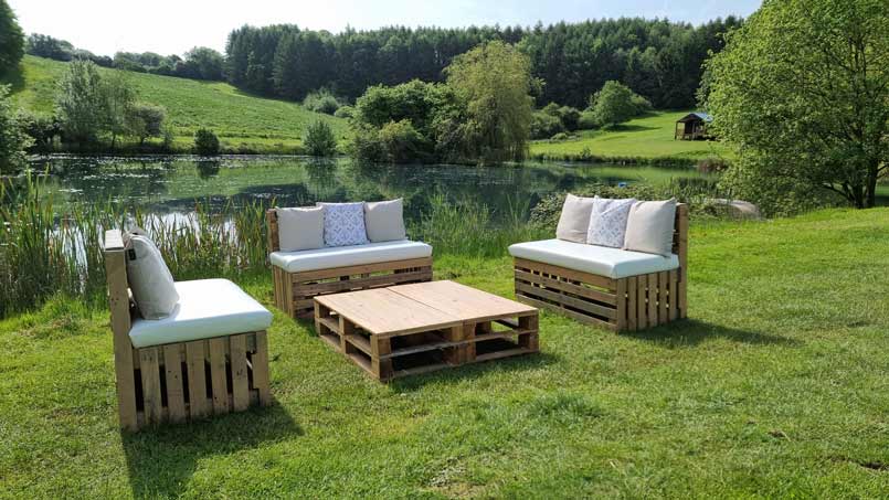 Outdoor Pallet benches and tables arranged next to a beautifull lake for a Cotswold marquee wedding.