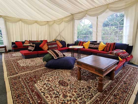 Arabian low-level chillout seating for hire, on top of cream Persian rugs in a marquee