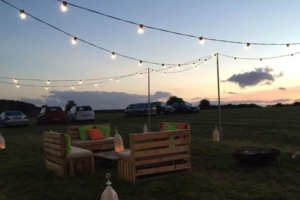 Festoon Lighting Supported by 3 Meter High Scaffold Poles, Illuminating a Festival Themed Wedding