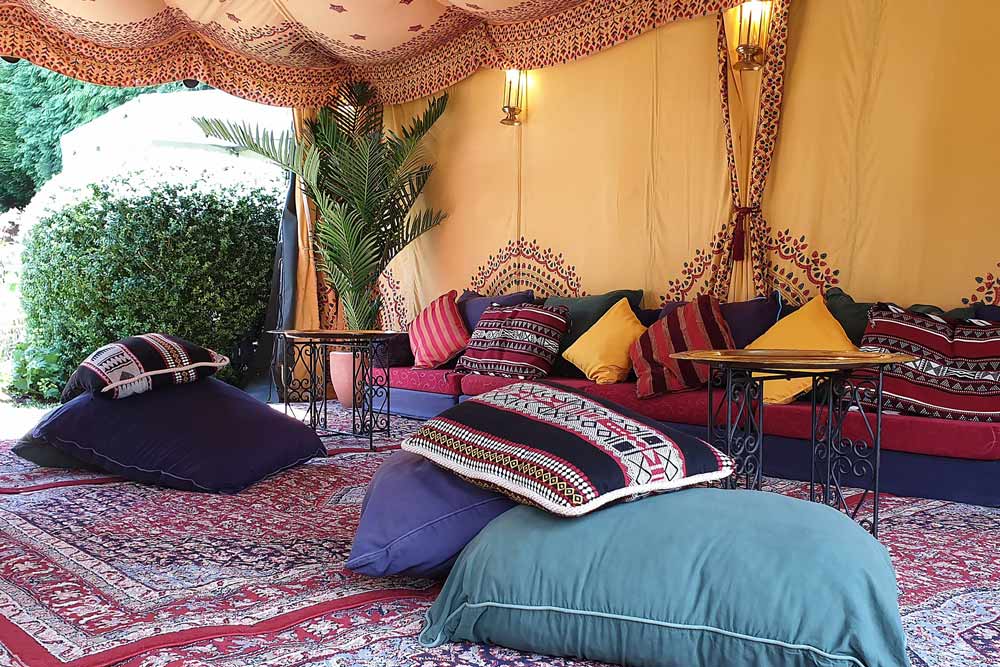 Low-level seating in The 4.5 x 4.5m Intimate Retreat Bedouin Tent suitable for garden parties of up to 20 people.