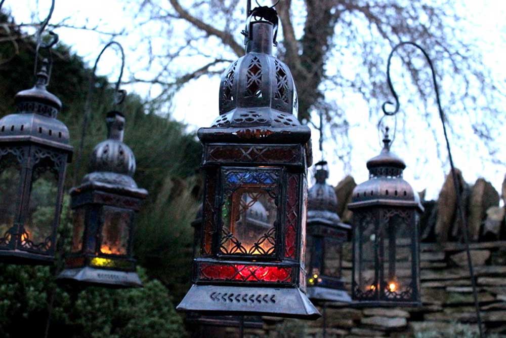 Iron and glass candle lanterns on poles, lighting a path to a marquee.