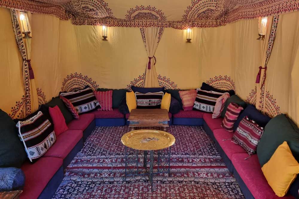 Low-level seating in The 3 x 6m Intimate Retreat Bedouin Tent suitable for garden parties of up to 20 people.