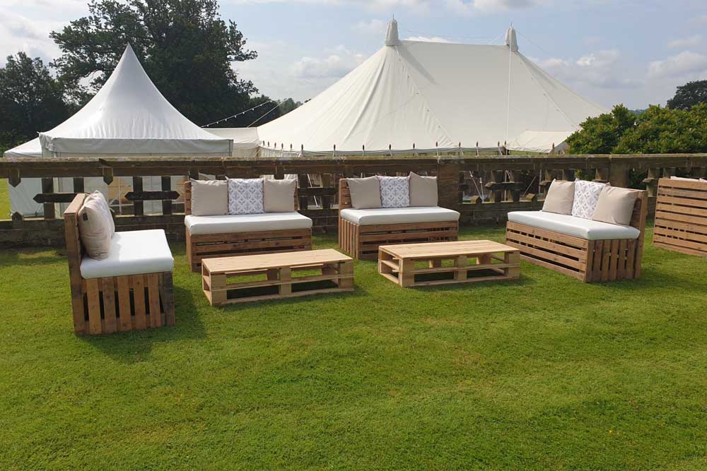 Outdoor pallet furniture in front of a large wedding marquee.