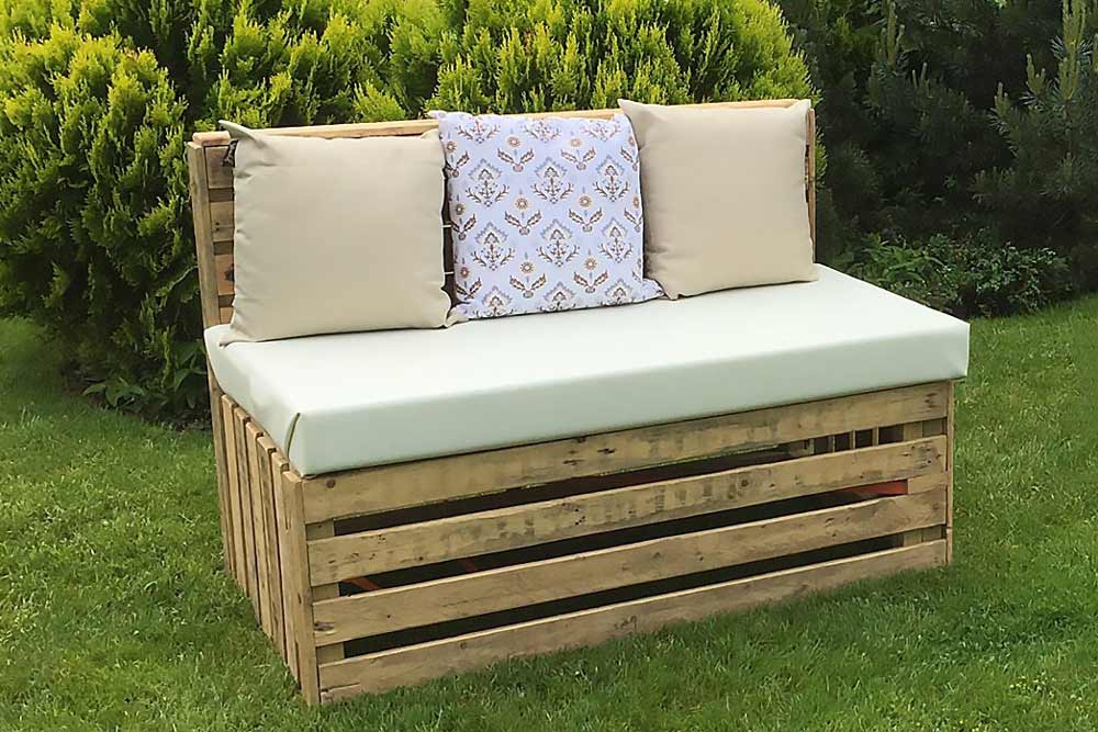 Outdoor pallet benches and coffee tables in front of a large wedding marquee.