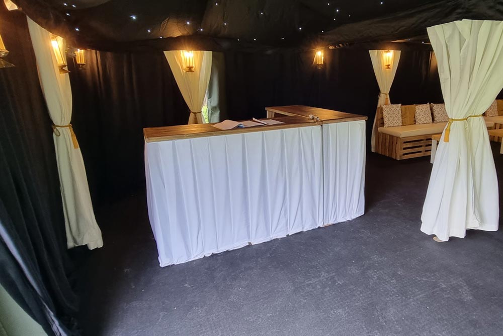A wooden event bar unit with a pleated white cover.
